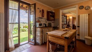 Una cocina con vistas, una mesa de madera, un microondas y un reloj colgado.
