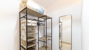 Un depósito con varios estantes, espacio para colgar, un espejo y una lámpara en la pared.