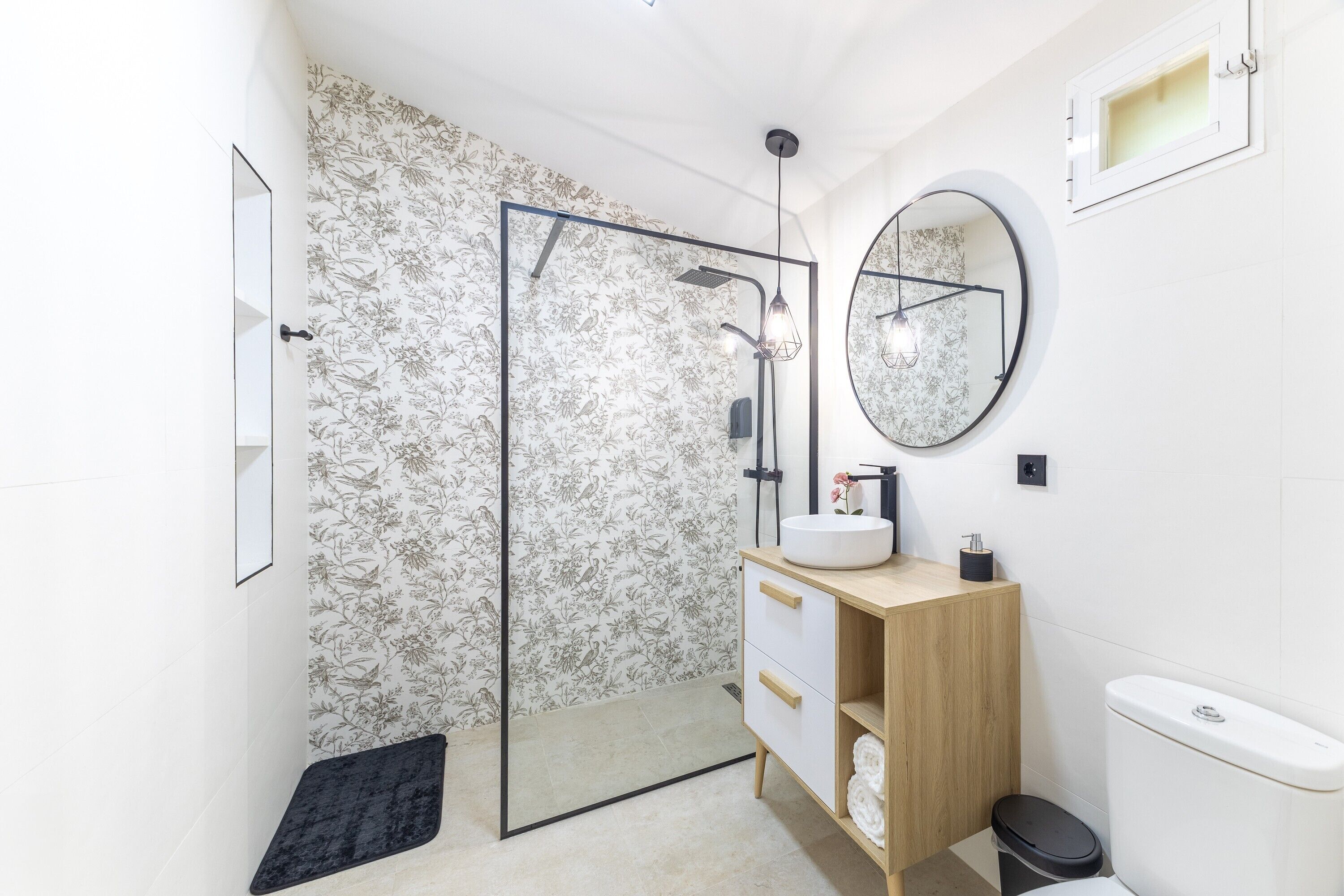 A modern bathroom with a shower, a sink, a toilet, and a mirror.