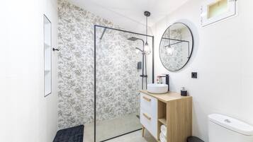 A modern bathroom with a shower, a sink, a toilet, and a mirror.