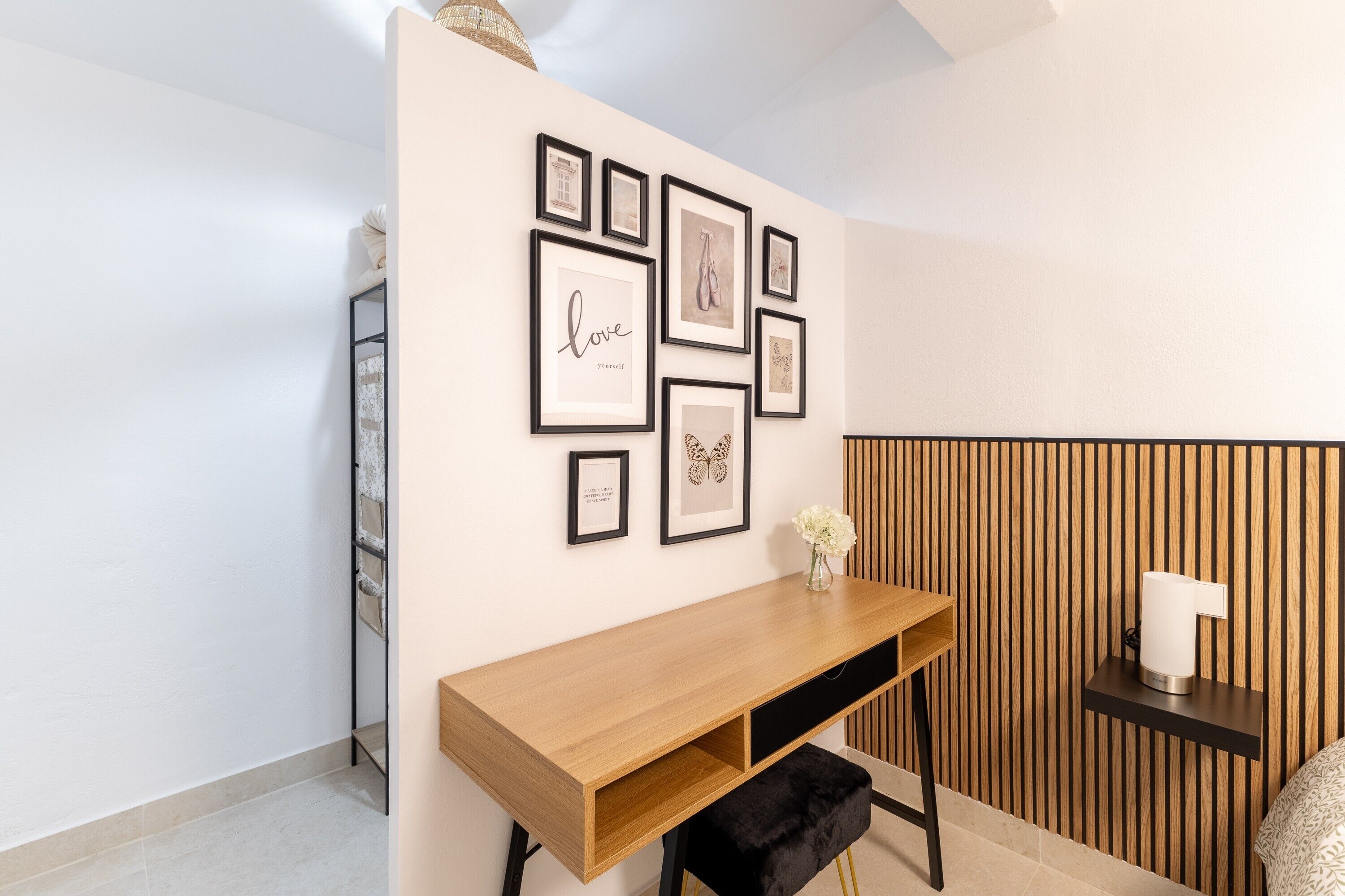 A modern room with a wooden desk, a black bench, and a wall decorated with framed pictures.