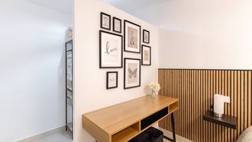 A modern room with a wooden desk, a black bench, and a wall decorated with framed pictures.