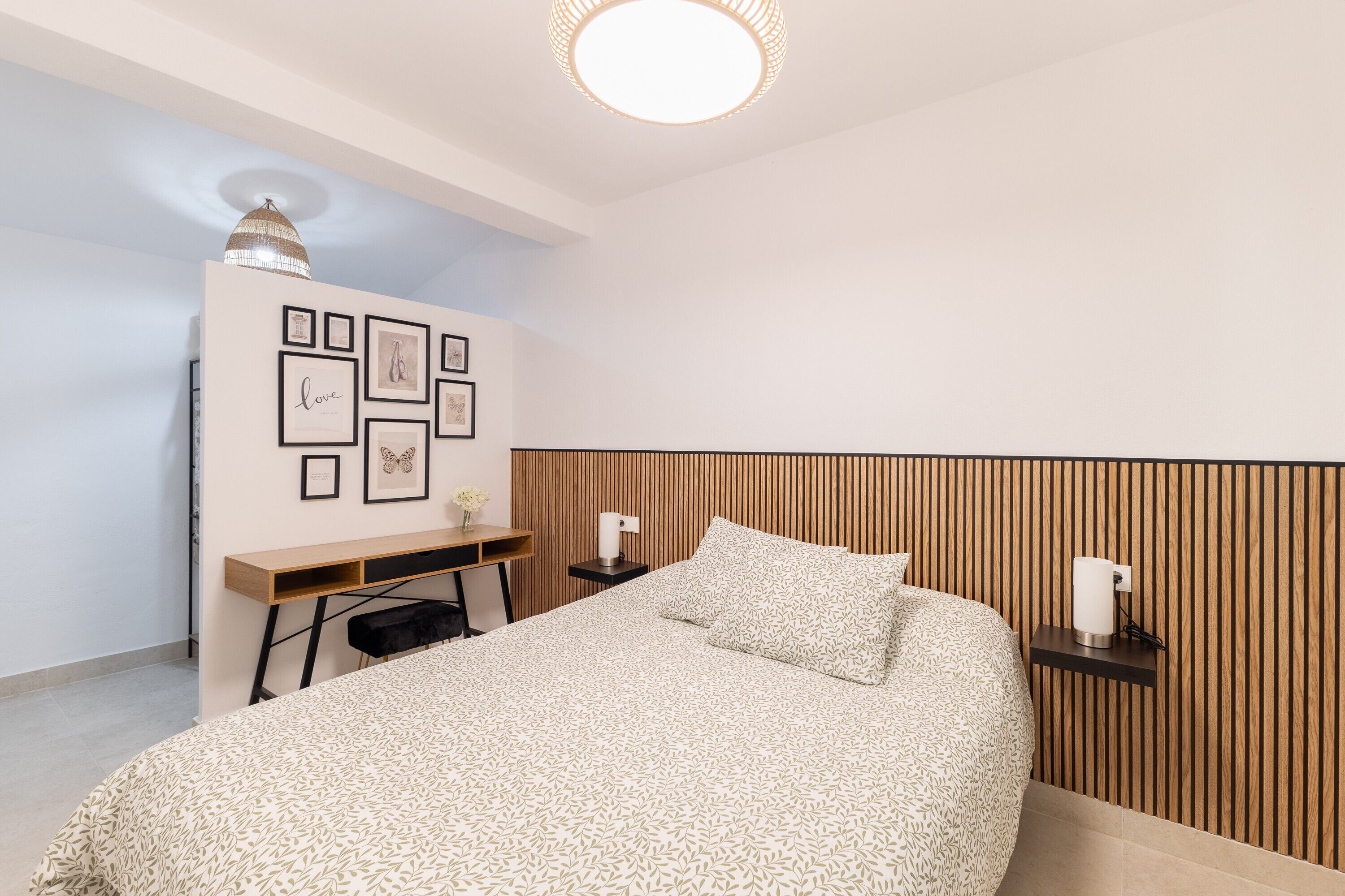 Une chambre à coucher avec un lit, un bureau et un mur orné de tableaux encadrés.