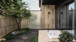 A modern outdoor spa area with a stone pathway, a large bathtub, and a glass-enclosed shower. - Younch Hotel Xi'An (Xi'an)