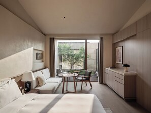 Ett hotellrum med en säng, en soffa, ett skrivbord och utsikt över en innergård.