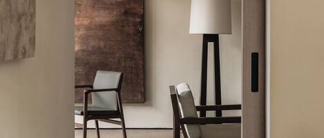 Una habitación moderna con diseño minimalista, que incluye dos sillas, un cuadro abstracto grande y una lámpara de pie.