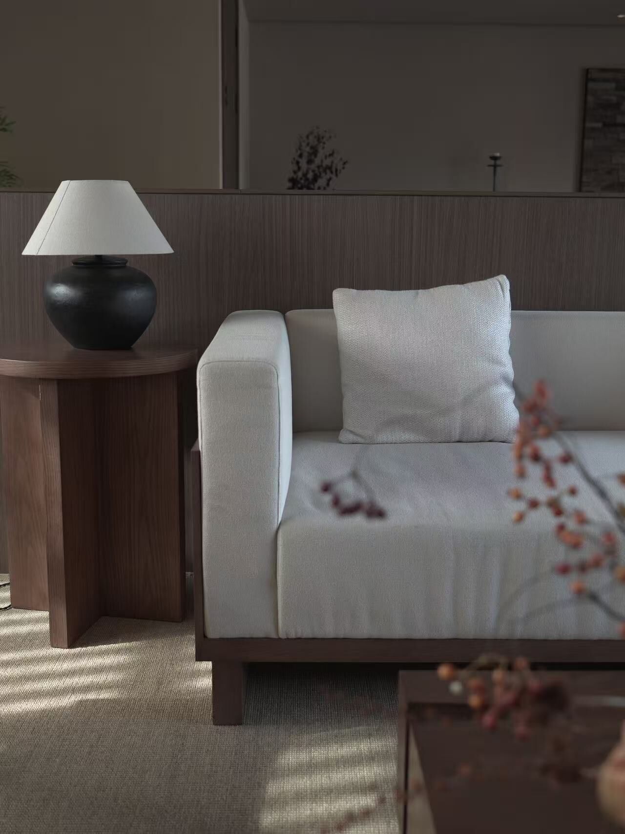 A modern living room with a sofa, a round wooden side table, and a floor lamp.