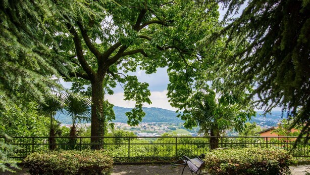 Ein steiniger Weg führt zu einer Bank mit Blick auf eine malerische Aussicht auf eine Stadt und Berge.