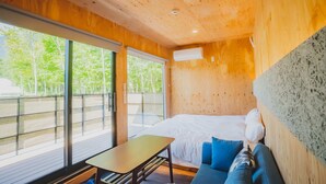 A wooden cabin room with a bed, a table, and a sofa. - SAUNA&Villa takibi (Makkari-mura)