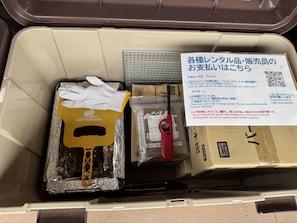 A suitcase with various items including a yellow cleaning glove, a red pen, and a cardboard box.