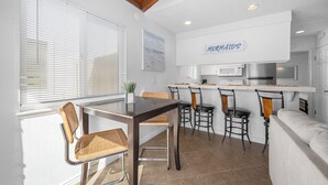 A compact kitchen with a bar area, white walls, and a ceiling with exposed beams.