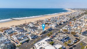 An aerial view of a coastal town with a beach, residential buildings, and a parking area. - Cozy Beach Duplex Steps to Sand and Shops (Newport Beach)