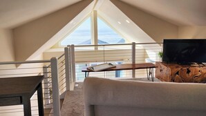 Una habitación estilo loft con un ventanal grande, un televisor de pantalla plana y una mesa de centro de madera.