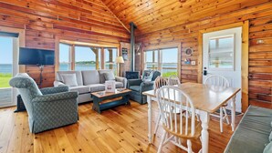 Ein Holzblockhaus-Innenraum mit einer Couch, Stühlen, einem Tisch und einem Kamin.
