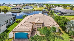 A residential area with a large house featuring a tiled roof, a swimming pool, and a garage.