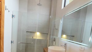 Une salle de bain moderne avec un plafond en bois, un grand miroir, un lavabo rond et une cabine de douche en verre.