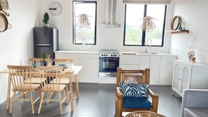 Une cuisine moderne avec des meubles blancs, une cuisinière et un coin repas comprenant des chaises et une table en bois.