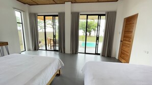 Une chambre d’hôtel avec deux lits, une porte-fenêtre coulissante donnant sur une piscine et une vue sur l’extérieur.