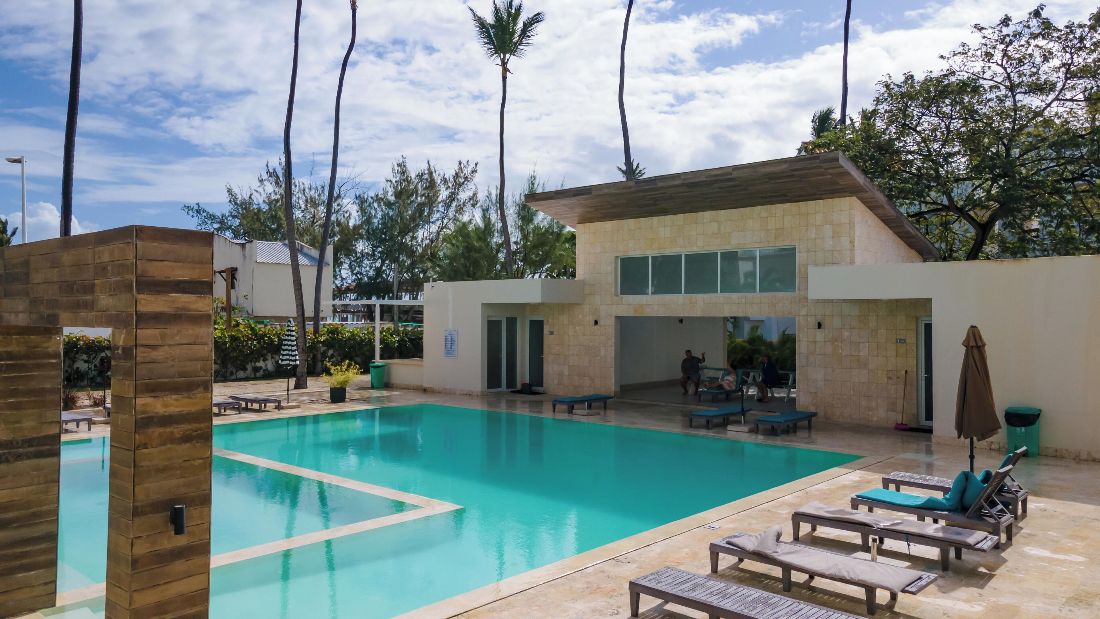 A swimming pool with lounge chairs and a building with large windows.