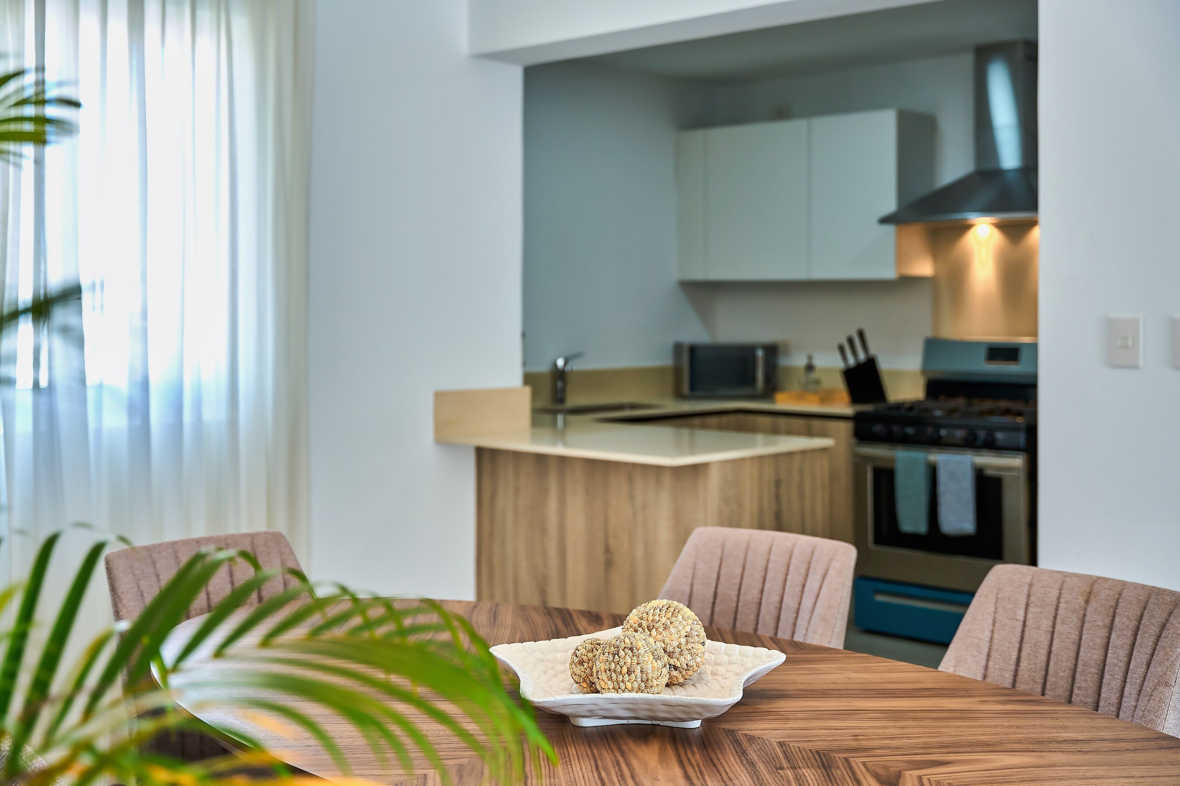 A modern kitchen with a central island, stainless steel appliances, and a dining area with a wooden table and chairs.