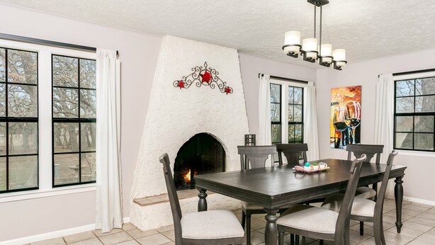 Un comedor con chimenea, una araña y una mesa con sillas.