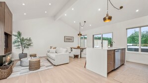 Amplia sala de estar con chimenea, un sofá, una mesa de comedor y una isla de cocina.