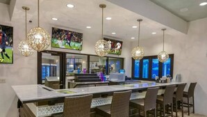 A modern kitchen with a central island, bar seating, and pendant lighting. - Welcome to Paradise | Windsor at Westside Resort (Kissimmee)
