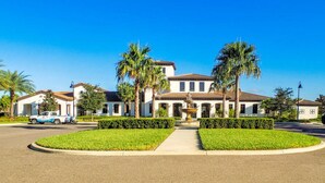 A large, two-story house with a symmetrical facade, a central entrance, and a well-maintained lawn with palm trees. - Welcome to Paradise | Windsor at Westside Resort (Kissimmee)