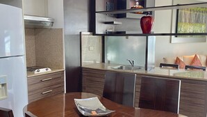 A modern kitchen with a built-in oven and microwave, a dining table with chairs, and a kitchen island with a sink and decorative items. - Deluxe Apartment with Guayas River view in Puerto Santa, Guayaquil (Guayaquil)