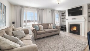 A living room with a beige sofa, a fireplace, and a flat-screen TV.