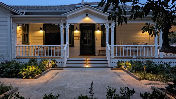 A two-story house with a front porch, a central door, and a small garden area. - Beautiful Magical Historic Webster House at Eleison Farms - Avocado Ranch 3 BD/2 BA (Carpinteria)