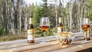 Een houten tafel met twee flessen Briksberg bier, twee glazen en een schaal olijven.