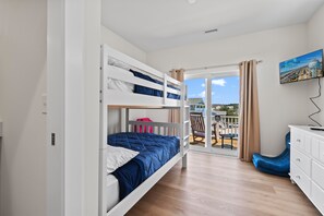 A room with a bunk bed, a desk, a chair, and a television.