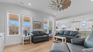 A modern living room with grey leather sofas, a coffee table, and a ceiling fan. - "Holden Memories" is a 5 Bedroom Second Row Home w/ PRIVATE Pool! (Holden Beach)