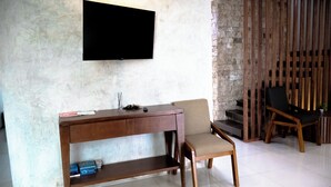 A modern room with a wooden desk, a chair, a television mounted on the wall, and a staircase with wooden railings. - Cozy 4-Sleeper Getaway w/ Pool & Laundry - Prime Mérida Mexico Stay!🌴 (Mérida)