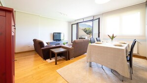 Una sala de estar moderna con un sofá, una televisión y una mesa de comedor lista para cuatro.