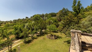 Ein angelegter Garten mit Wegen, Bäumen und einer Steinmauer.