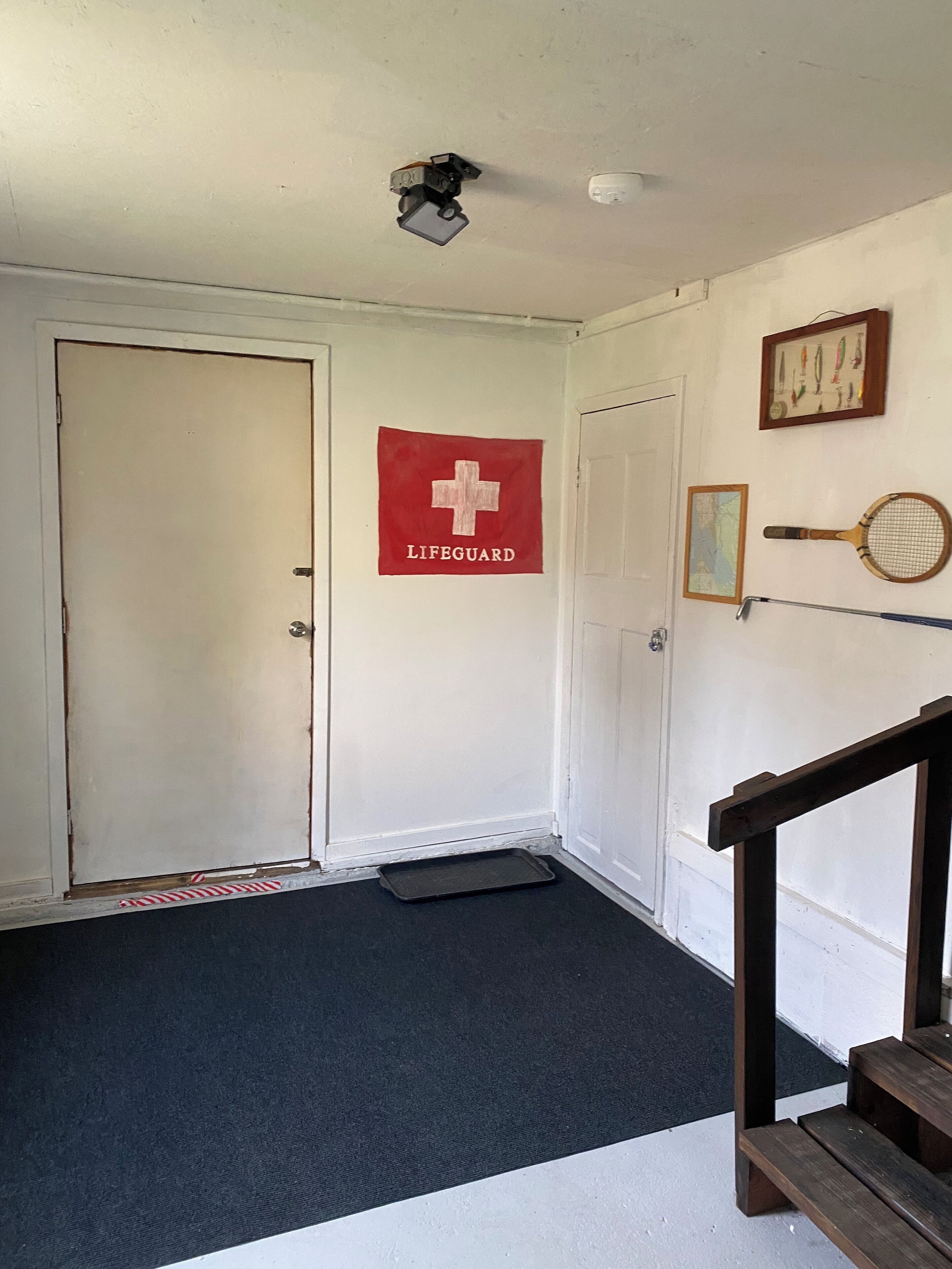 A hallway with a lifeguard sign, a framed map, and a tennis racket on the wall.