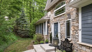 A stone house with a porch, a large tree, and a bench. - Hot Tub-Movie Rm-Game Rm (Asheville)