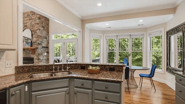 A kitchen with granite countertops, a stone backsplash, and a dining area with a table and chairs. - Hot Tub-Movie Rm-Game Rm (Asheville)