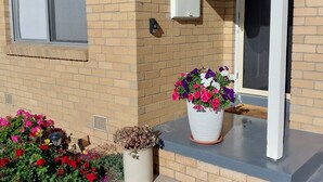 A building with a brick facade, a sign reading "SANTA MARIA", a white door, and a potted plant with flowers on the porch. - Cosy Corio Gateway - 2 Mins to Spirit of Tasmania (Corio)