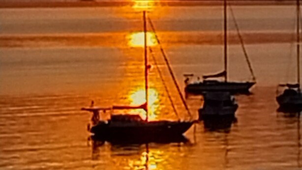 A sunset over a calm body of water with several boats anchored. - Cosy Corio Gateway - 2 Mins to Spirit of Tasmania (Corio)