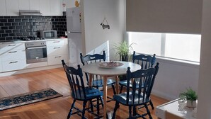 A modern kitchen with white cabinets, a black tiled backsplash, and a built-in microwave. - Cosy Corio Gateway - 2 Mins to Spirit of Tasmania (Corio)