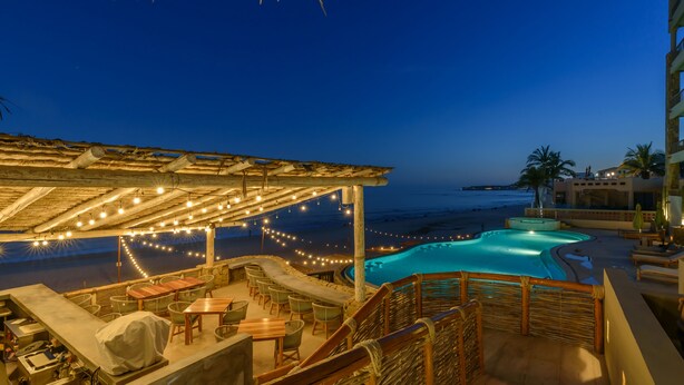 A rooftop pool area with a covered seating area, string lights, and a view of the ocean. - Beachfront, Ocean View, Amazing Location! (San José del Cabo)