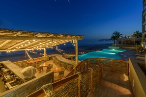 A rooftop pool area with a covered seating area, string lights, and a view of the ocean. - Beachfront, Ocean View, Amazing Location! (San José del Cabo)