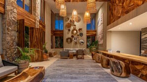 A spacious living area with a large wooden dining table, comfortable seating, and a stone accent wall. - Beachfront, Ocean View, Amazing Location! (San José del Cabo)