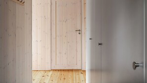 A room with wooden walls and a wooden floor, featuring a door with a handle and a metal lock. - Renstråket 1001 by Interhome (Tännäskröket)