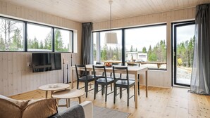 A modern cabin interior with a dining area, a sofa, and a TV mounted on the wall. - Renstråket 1001 by Interhome (Tännäskröket)