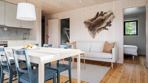 A modern interior with a dining area, a sofa, and a mounted animal hide. - Renstråket 1001 by Interhome (Tännäskröket)