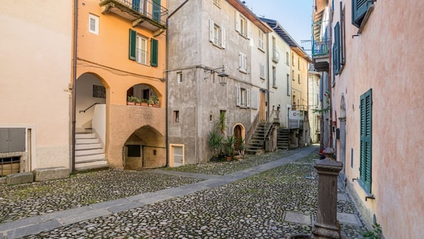 Eine gepflasterte Straße, gesäumt von historischen Gebäuden mit Balkonen und Rundbögen.